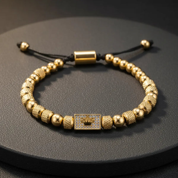 Golden beaded bracelet with a crown pattern on the plate.