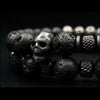 Close-up of black lava stone beaded bracelet featuring detailed stainless-steel skull charm